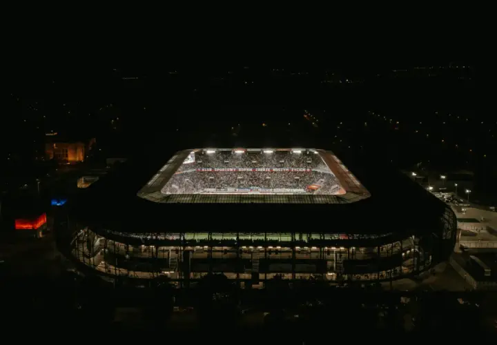 Nocny widok stadionu Górnik Zabrze. Trybuny wypełnione kibicami, widoczny napis "KLUB SPORTOWY GÓRNIK ZABRZE NASZYM ŻYCIEM". Pojemność stadionu robi wrażenie.
