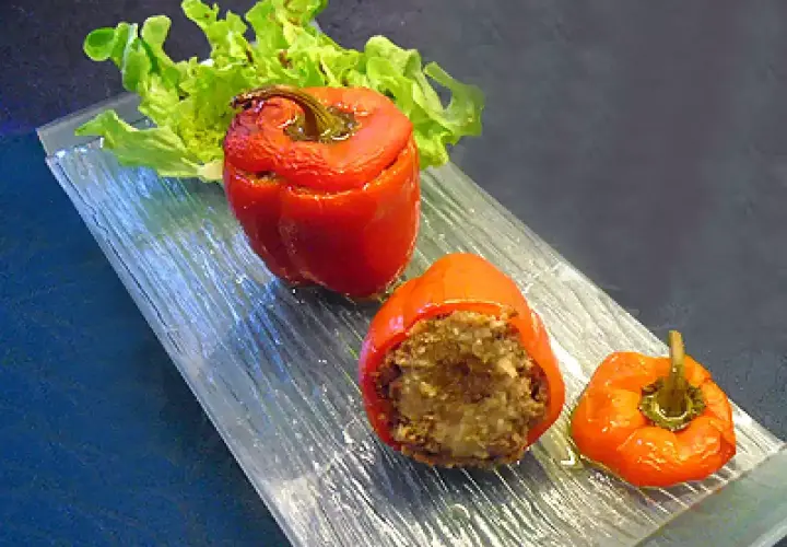 Poivrons farcis à la chair à saucisse, servis sur un plateau en verre avec une feuille de laitue.