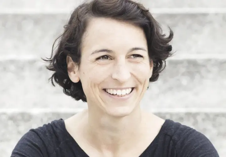 Lachende Frau mit kurzen Haaren, die an Madame Moneypenny Kritik erinnert.