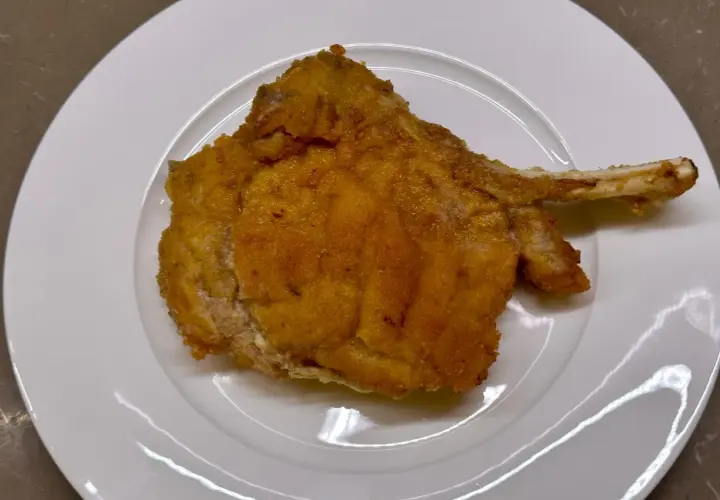Cotoletta alla valdostana dorata e croccante su piatto bianco, pronta per essere gustata.