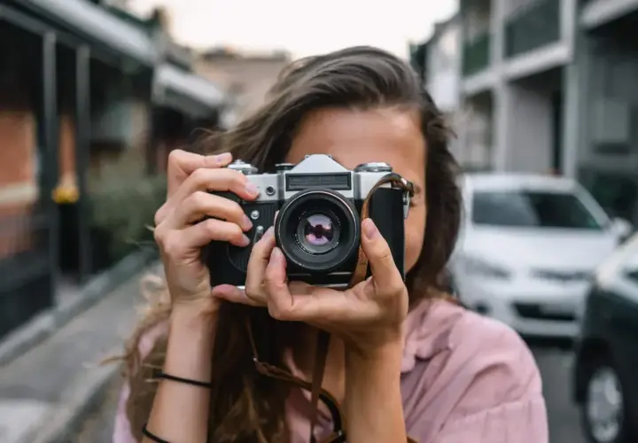 Dziewczyna z aparatem w rękach, gotowa na swój pierwszy kurs fotografii od podstaw.
