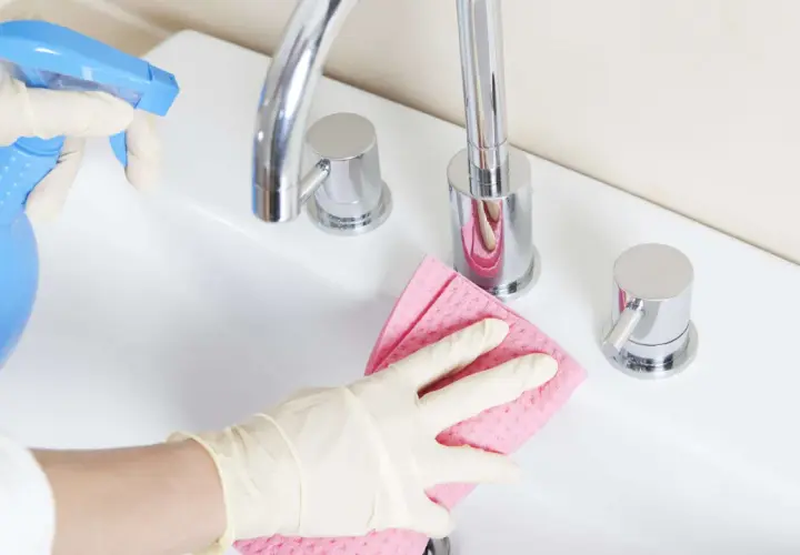 Mit Handschuhen und einem selbstgemachten Badreiniger wird das Waschbecken blitzblank.