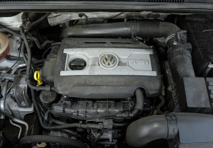 Silnik 2.0 TSI Volkswagena, widok z góry. Widać pokrywę silnika z logo VW i napisem TSI, przewody i inne elementy komory silnika.