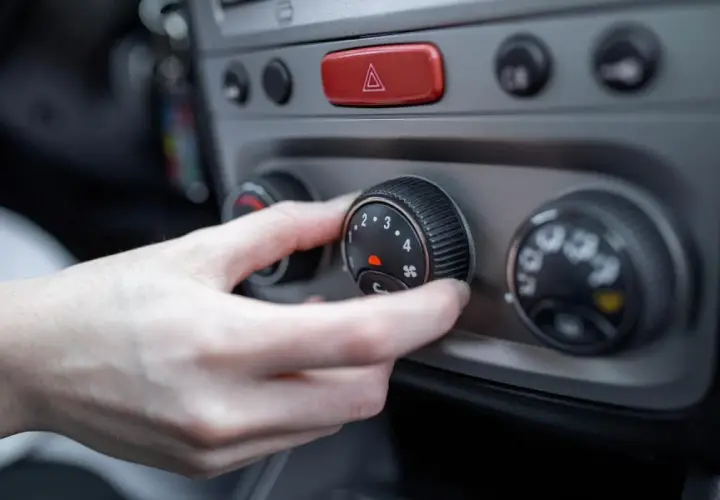 Mano ajustando el control del aire acondicionado a modo frio. El dial muestra números del 1 al 4 y un icono de ventilador.