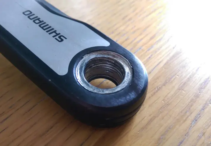 Close-up of a Shimano crank arm showing the threaded hole for pedal installation. This detail is crucial for understanding the correct mtb pedal thread size.