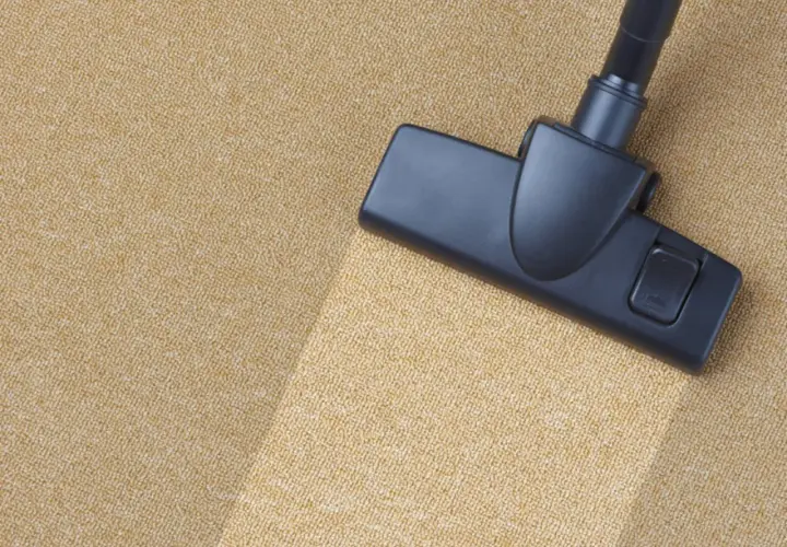Cabezal de aspiradora limpiando una alfombra beige. Un ejemplo visual de como limpiar una alfombra para dejarla impecable.