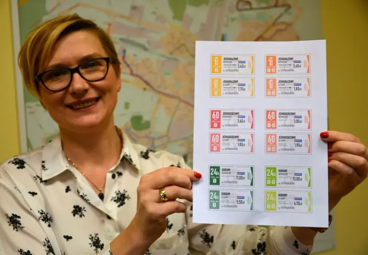 Kobieta prezentuje wydrukowane bilety ZTM Kielce. Na kartce widać różne rodzaje biletów jednorazowych, godzinnych i dobowych, z podanym cennikiem.