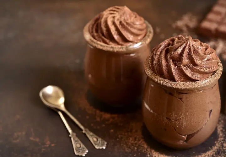 Délicieuse présentation de mousse au chocolat, garnie de cacao, prête à être dégustée avec des cuillères élégantes.