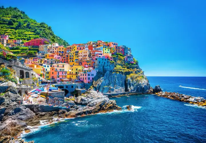 Village coloré accroché à la falaise, vue sur la mer bleue. Un gîte Cinque Terre parfait pour des vacances inoubliables.