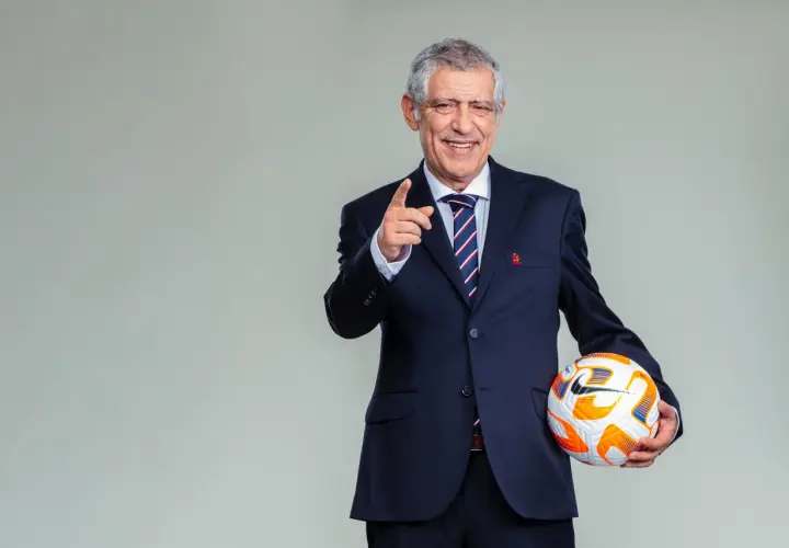 Fernando Santos, w garniturze i z piłką, wskazuje palcem, gotowy do gry.