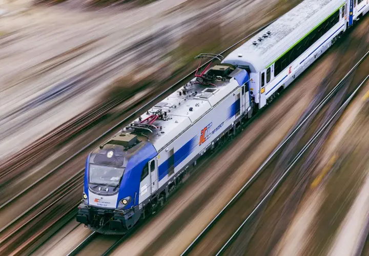 Pędzący pociąg PKP Intercity EU160 na torach, rozmyte tło sugeruje dużą prędkość.