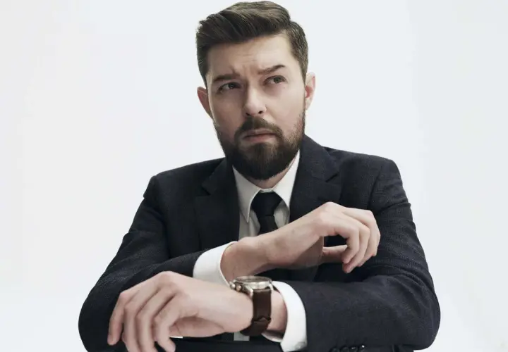 Remigiusz Mróz, znany pisarz, w eleganckim garniturze, z zamyśloną miną. Może planuje kolejną premierę książki, a może wizytę u dentysty?