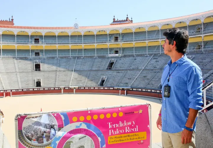Un guía turístico en la plaza de toros de Madrid, con los tendidos y el Palco Real al fondo.