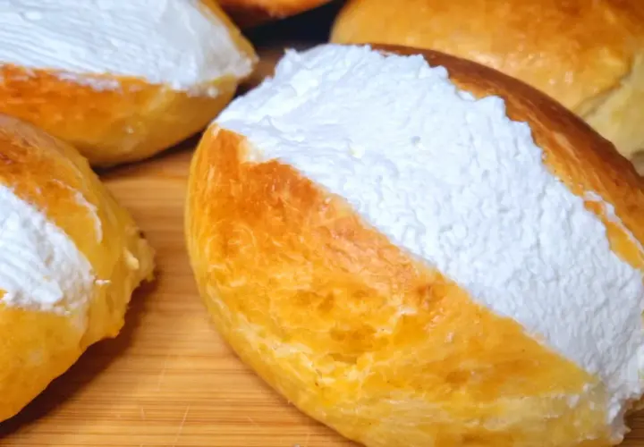 Maritozzi ricetta originale: soffici panini dolci farciti con abbondante panna montata, pronti per essere gustati.