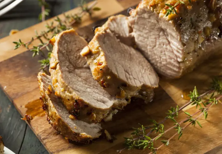 Tranches de filet mignon de veau rôti, juteux et savoureux, garnies de thym frais sur une planche à découper en bois.