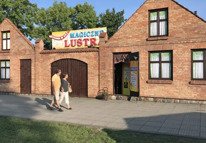 Para spaceruje obok budynku z napisem "Magiczne Lustra Łeba".