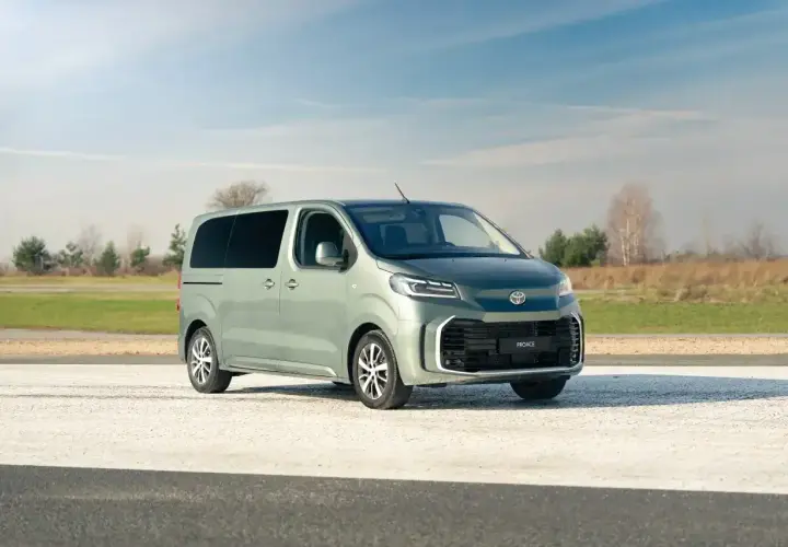 Nowy, zielony Toyota Proace na tle nieba i pól. Idealny do rodzinnych podróży i transportu.