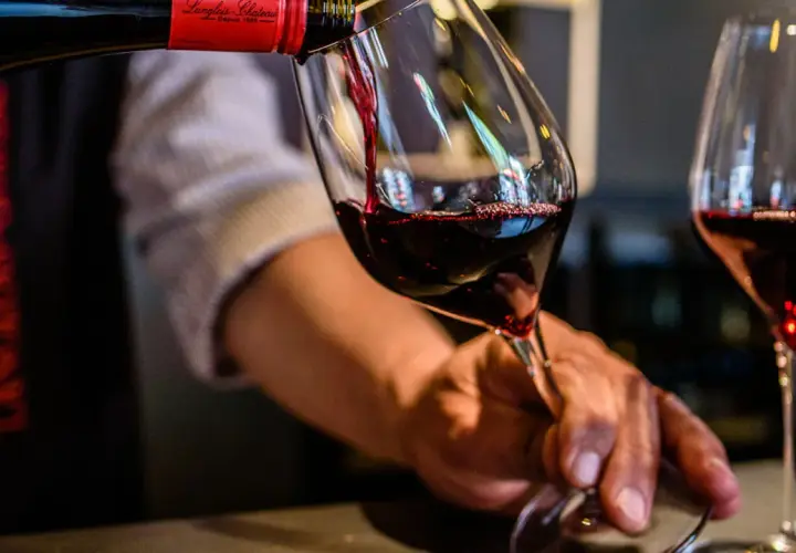 Service d'un vin rouge, idéalement servi à la bonne **température Saumur Champigny**. Le vin est versé dans un verre, avec une autre verre déjà rempli.