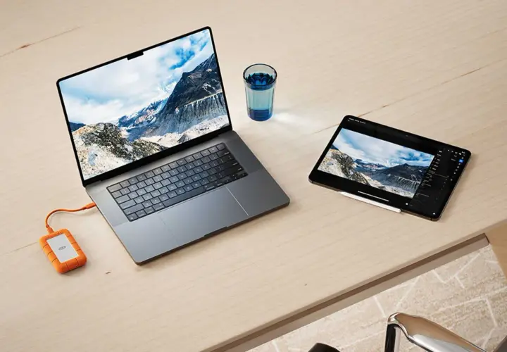 Ein Laptop und ein Tablet mit Berglandschaft, verbunden mit einer externen Festplatte. Ideal für den Datenaustausch zwischen exFAT Windows und Mac.