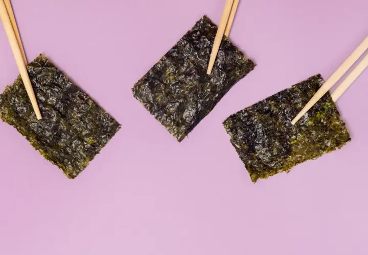 Tre fogli di alga nori, tenuti da bacchette, evidenziano le loro proprietà nutritive.