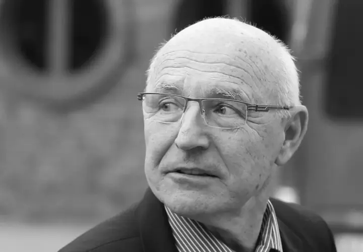 Portret starszego mężczyzny w okularach, który wygląda jak doświadczony lenczyk trener piłkarski, zamyślony.