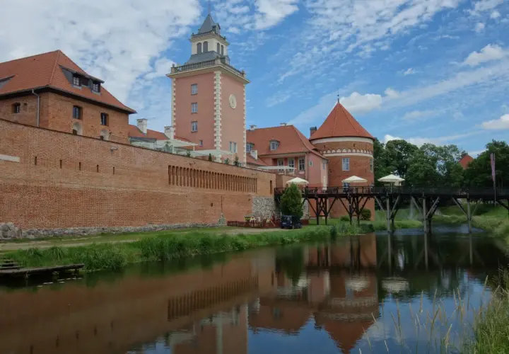 Zamek w Lidzbarku Warmińskim, z wieżą i fosą, to jedna z głównych atrakcji regionu.