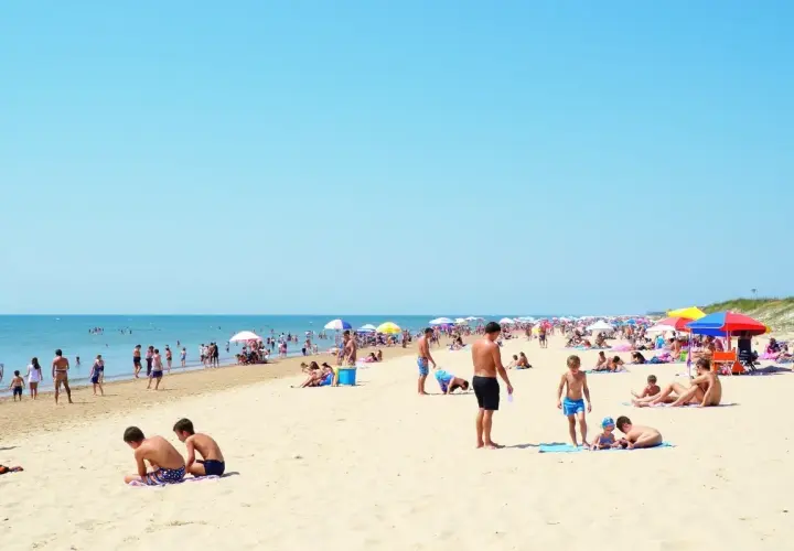 Tłum ludzi na piaszczystej plaży, szukających odpowiedzi na pytanie: gdzie najbliżej nad morze z Warszawy.