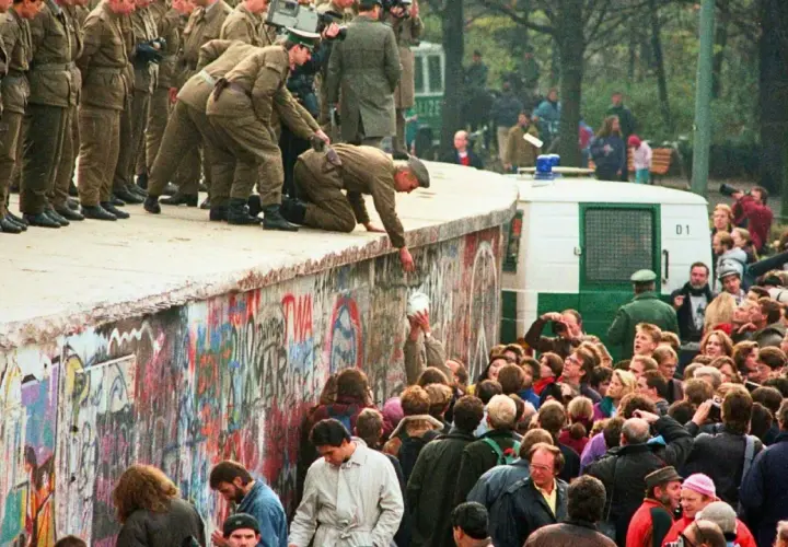 Menschen feiern die Wiedervereinigung Deutschlands am Berliner Mauer. Soldaten helfen Menschen über die Mauer. Eine Zusammenfassung der Freude und des Wandels.