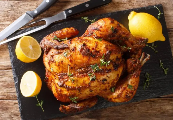 Pollo asado al horno, dorado y jugoso, con limones y hierbas frescas. ¡Listo para servir!