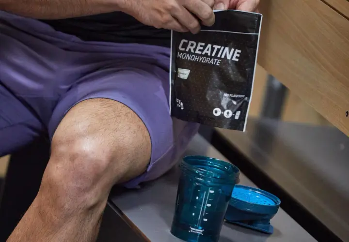 Kreatyna monohydrat - co daje przedtreningówka? Worek z kreatyną i shaker czekają na trening.