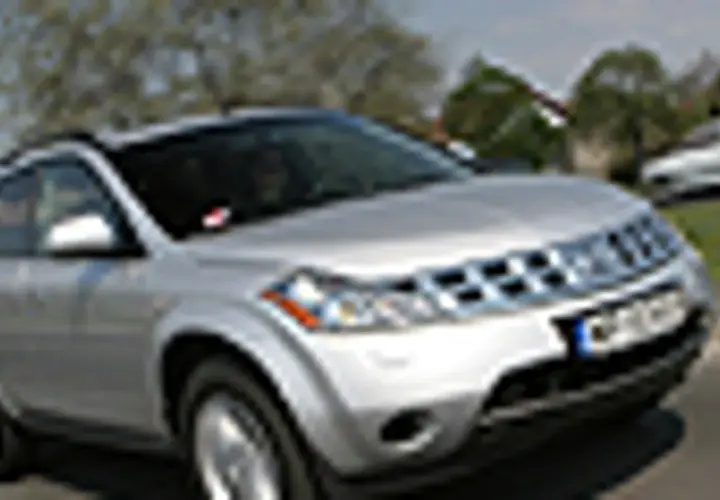 Srebrny Nissan Murano 3.5 V6 na drodze, z drzewami i innymi samochodami w tle.