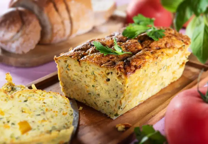 Pyszny pasztet z cukinii, lekki i aromatyczny, idealny na kanapki. Obok kromki chleba i pomidorów.