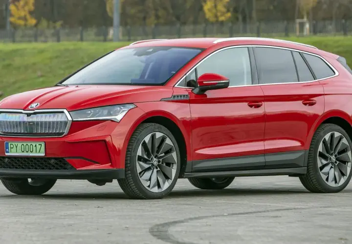Czerwona Skoda Enyaq na tle zieleni. Sprawdź aktualną skoda enyaq cena i wybierz swój wymarzony samochód elektryczny.