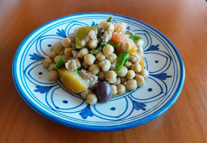 Un'appetitosa insalata di ceci alla siciliana, con pomodoro, olive e verdure fresche, servita su un piatto decorato.
