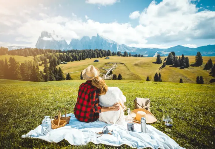 Para spędza **weekend majowy** na pikniku w górach, otoczona zielenią i majestatycznymi szczytami.