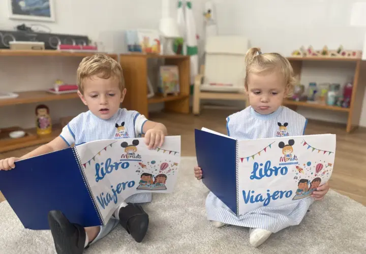 Niños leyendo un libro viajero infantil, con dibujos de cohetes y globos aerostáticos.