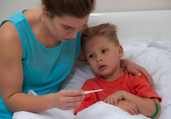 Mamma controlla la febbre al bambino, preoccupata per la quarta malattia.