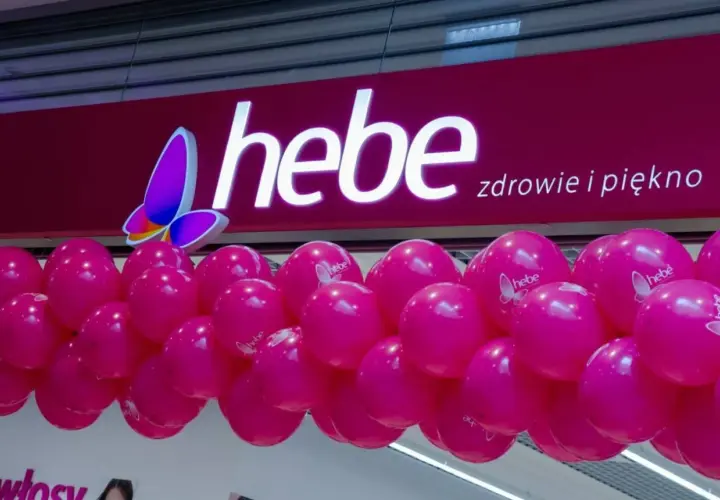 Logo Hebe z motylem i girlanda różowych balonów.