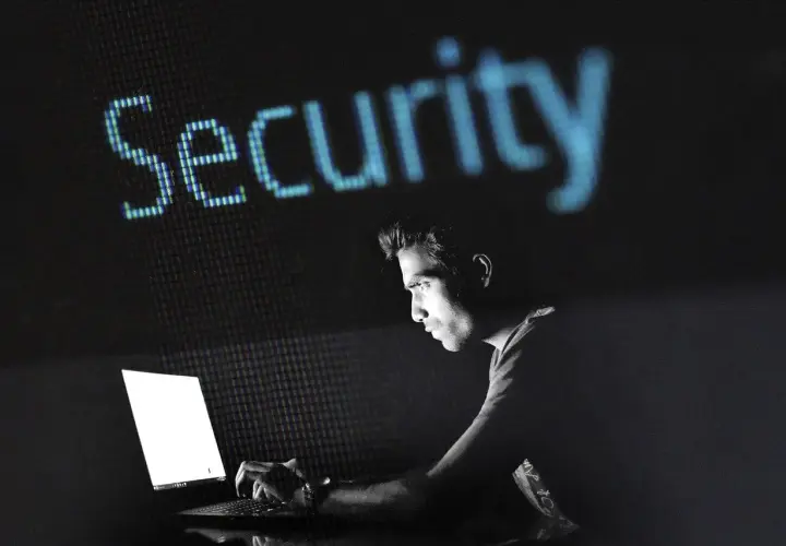 Mężczyzna pracuje przy laptopie, nad nim świeci napis "Security". Dowiedz się, jak zahasłować plik Excel, by chronić swoje dane.