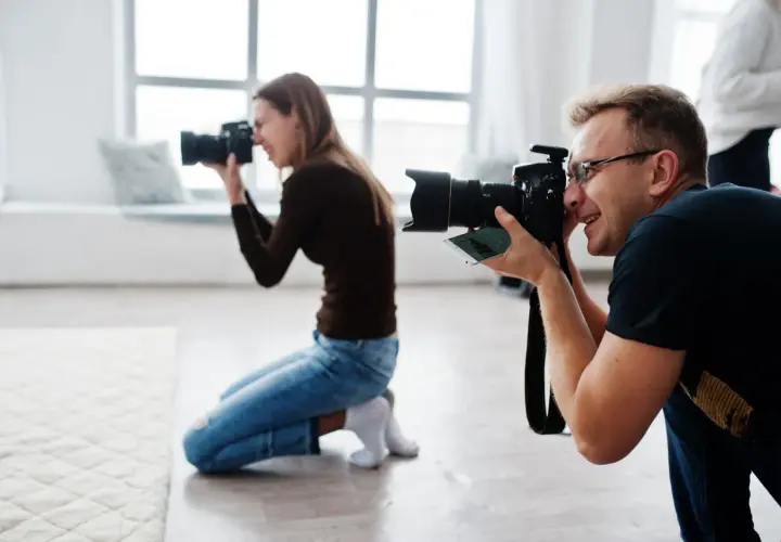 Mężczyzna i kobieta uczą się, jak zostać fotografem, ćwicząc z aparatami w studiu.