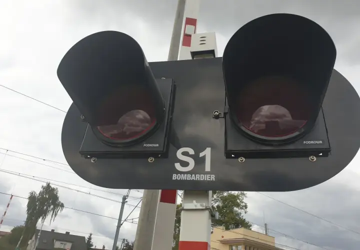 Dwa czerwone światła na przejeździe kolejowym Bombardier S1, gotowe do zatrzymania ruchu.