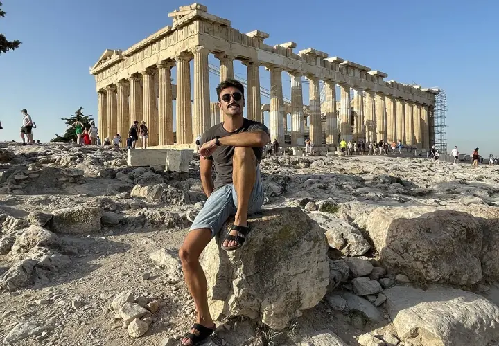Hombre sentado en la Acrópolis, disfrutando de la vista del Partenón. ¡Una parada obligatoria si buscas qué ver en Atenas en 2 días!