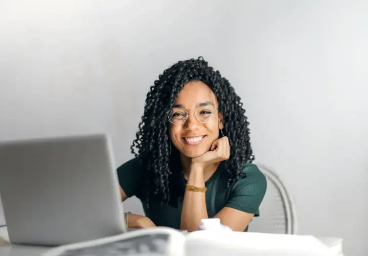Donna sorridente con occhiali, laptop e libri. Si chiede dopo quante sedute di psicoterapia si vedono i risultati.