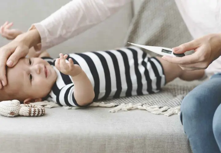 Mamma controlla la febbre al neonato di 1 mese con un termometro. 38.0°C.