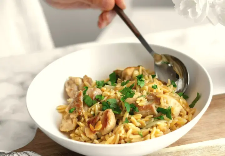 Miseczka z kurczakiem i makaronem orzo, posypana natką pietruszki. Idealne na proste przepisy na obiad.