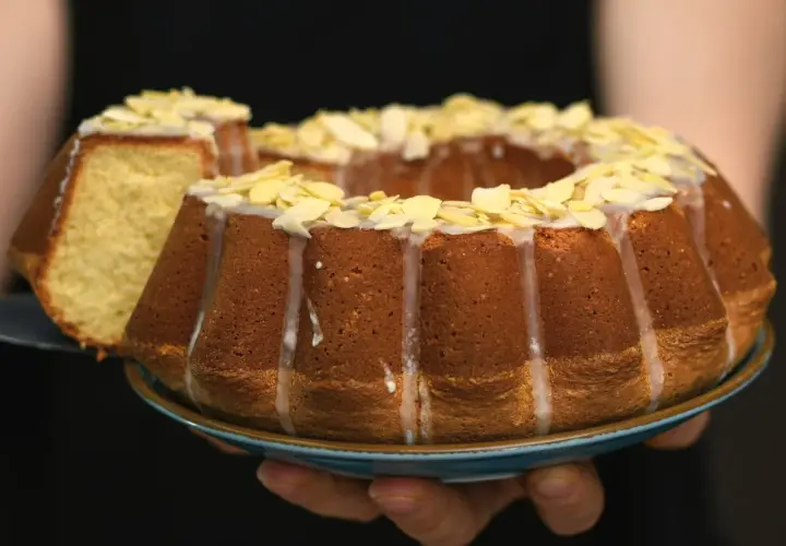Pyszna babka na oleju siostry Anastazji, udekorowana lukrem i płatkami migdałów, z odciętym kawałkiem.