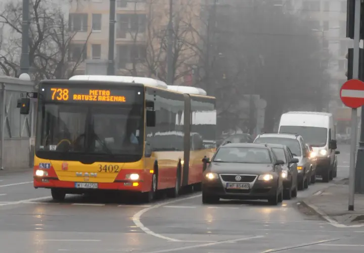 Autobus linii 738 z napisem "METRO RATUSZ ARSENAŁ" w ruchu miejskim, w tle samochody i budynki.