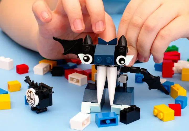 Kinderhände bauen mit bunten Klemmbausteinen einen Fledermaus-Charakter. Ein beliebter Klemmbaustein Hersteller ermöglicht kreativen Spielspaß.