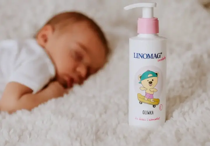 Śpiące dziecko obok butelki oliwki dla noworodka Linomag.
