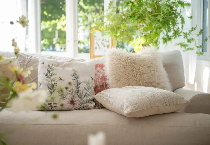 Mysiga kuddar i soffan inspiration: en blommig kudde med bin, en fluffig beige kudde och en texturerad ljus kudde skapar en ombonad känsla.